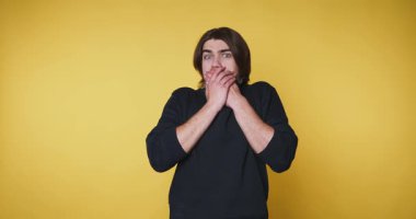 Genç adamın bej arka planda ellerini göğsünün yakınına koyarken sevinç ve heyecanı ifade eden görüntüleri.