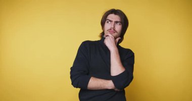 Genç adamın bej arka planda ellerini göğsünün yakınına koyarken sevinç ve heyecanı ifade eden görüntüleri.