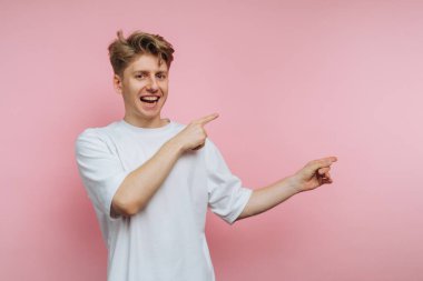 Pembe arka planda beyaz tişörtlü genç adam..