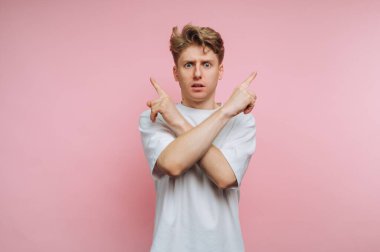 Pembe arka planda çapraz kolları olan genç bir adam zıt yönlere bakıyor..