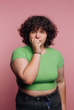 Pembe arka planda yeşil saçlı, kıvırcık saçlı genç kadın..