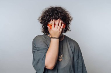 Kıvırcık saçlı, elleri ve elleri olan, güneş gözlüğü takan biri..