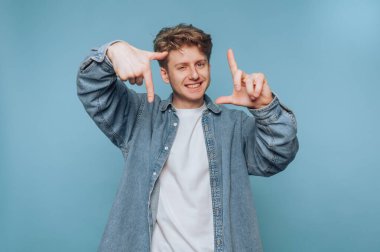 Mavi arka planda elleri olan kot gömlekli genç adam..