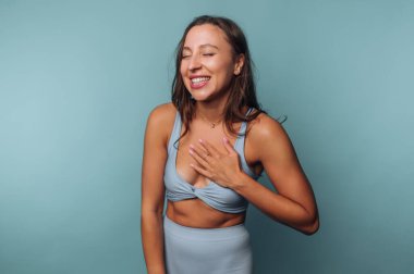 Mavi etekli gülümseyen kadın, deniz mavisi bir arka planda.