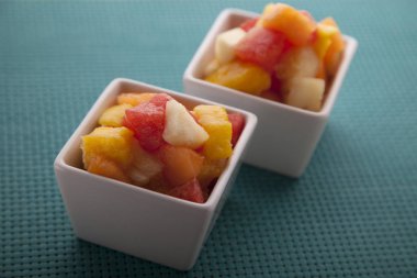Meyve salatası karışımı kavun, muz, karpuz, portakal ve ananas küçük porselen kase, kahvaltı veya sağlıklı snack, kilo verme kavramı