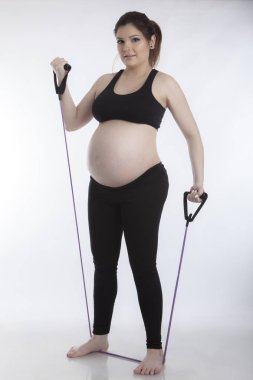 Hamile kadın beyaz arka plan üzerinde jimnastik egzersizleri yapıyor