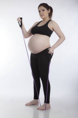 Hamile kadın beyaz arka plan üzerinde jimnastik egzersizleri yapıyor