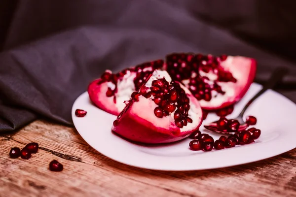 Olgun kırmızı nar beyaz tabakta metalik kaşıkla kesmek