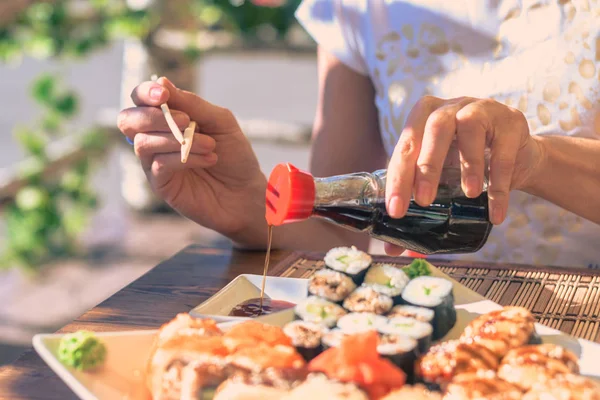 Soya sosu suşi Sokak kafede beyaz tabakta şişe kadınla