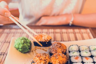 Kadın Asya yemek çubukları ile Sokak kafede Suşi yiyor