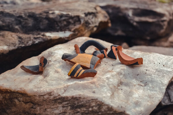 кусочки разбитой антикварной вазы на камне
