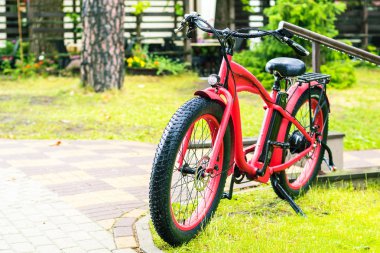 Yağmurlu günde yeşil çimenlerin üzerinde duran geniş lastikler ile kırmızı electrobicycle