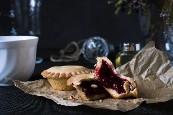 Cookies with jam on brown paper on black backgroung with white cup