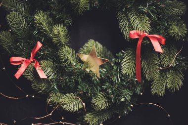 Mevsimlik karanlık yeni yıl arka plan köknar ağacı çelenk kırmızı şerit ve altın bir yıldız ile