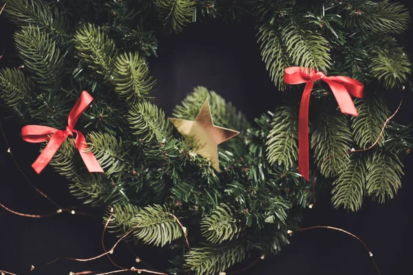 Mevsimlik karanlık yeni yıl arka plan köknar ağacı çelenk kırmızı şerit ve altın bir yıldız ile