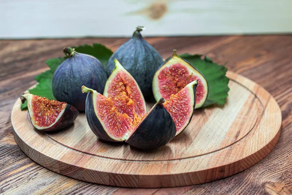 A few cuted figs on a plate on an old wooden background — Stock Photo, Image