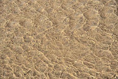 Kumsalda dalgalanan deniz suyunun yüzeyinde. Su yüzeyi arkaplanı, doku.