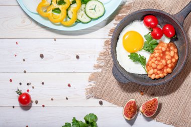 Vejetaryen İngiliz kahvaltısı - dökme demir tavada kızarmış yumurta, kiraz domatesleri, fasulye ve sebzeler