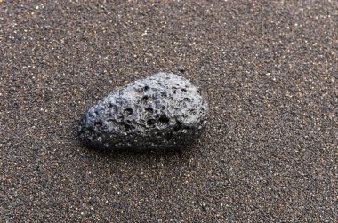 Plajın karanlık kumüzerinde siyah lav taşı