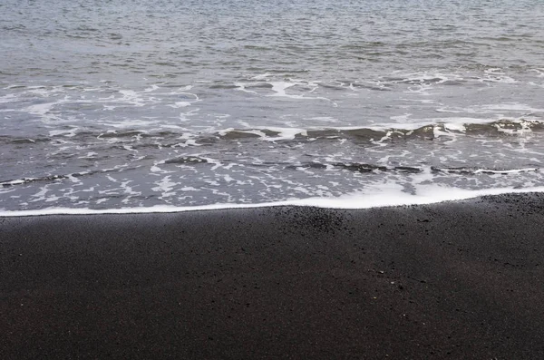 黒い砂の上の小さな海のサーフィン — ストック写真