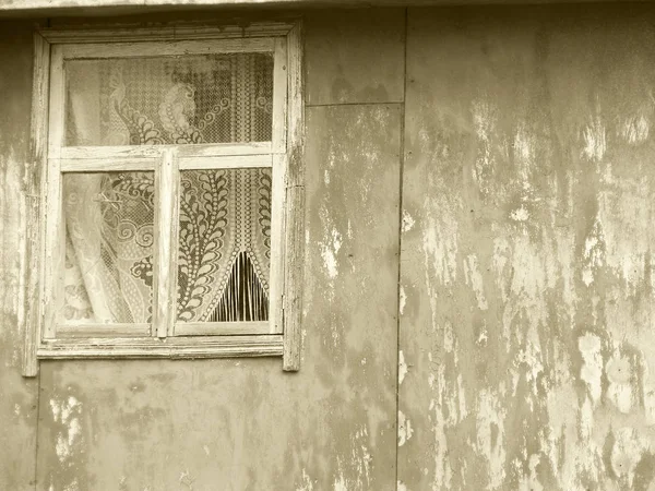 Old deserted house, window on shabby wall, monochrome photo;