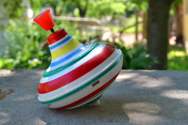 Вихрь для детей концептуальное фото на фоне размытого лета, старый пластиковый вихрь игрушки с красной ручкой
