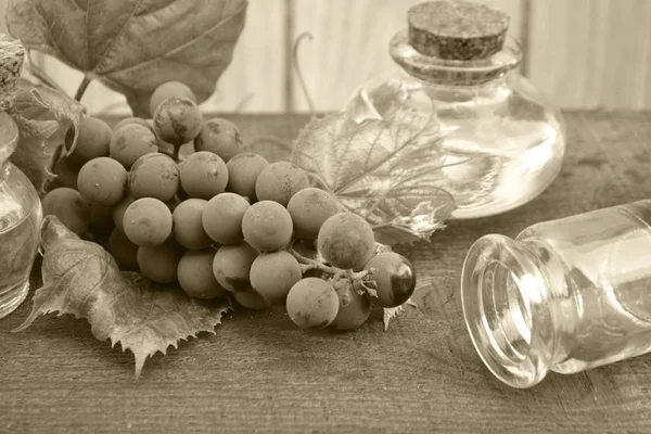 Bottle with grape seed oil on rustic background. Monochrome photo. Fruit, antioxidant.