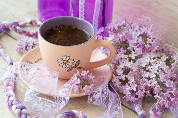 Xícara violeta de café da manhã ou cappuccino e delicado rosa, roxo, flores lilás. Conceito do dia das mães. Pequeno-almoço acolhedor — Fotografia de Stock