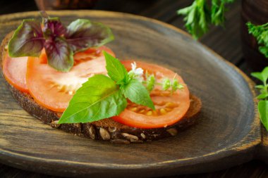 Koyu ahşap bir arka planda domates ve fesleğen..