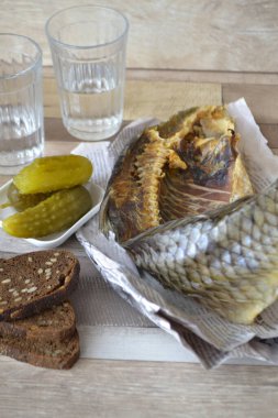 Votka, kuru balık, turşu, gazetedeki masa örtüsünde siyah ekmek. Dikey resim