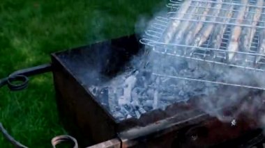 Çelenk. Erkeklerin eli barbeküdeki balık kafesini çeviriyor. Köyün yaşam tarzı. Izgaradaki Belone Belone. Izgara. Açık ateşte kızartılmış balık pişirmek. Barbekü, dışarıda. 