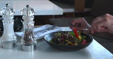 Sakallı bir adam gün ışığında taze yemek yiyor. Yetişkin bir adam iş yemeği sırasında kafede salata yiyor. Sağlıklı beslenme konsepti. Vejetaryenlik
