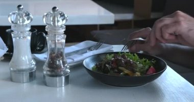 Sakallı bir adam gün ışığında taze yemek yiyor. Yetişkin bir adam iş yemeği sırasında kafede salata yiyor. Sağlıklı beslenme konsepti. Vejetaryenlik