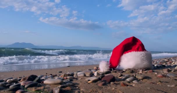 穏やかな波と熱帯の砂浜でクリスマスサンタクロースの帽子 冬休みだ島での新年のお祝い コンセプト — ストック動画