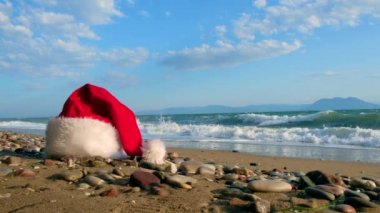  Tropikal kumlu sahilde sakin dalgalarla Noel Baba şapkası. Kış tatili Adada yeni yıl kutlaması. Kavram