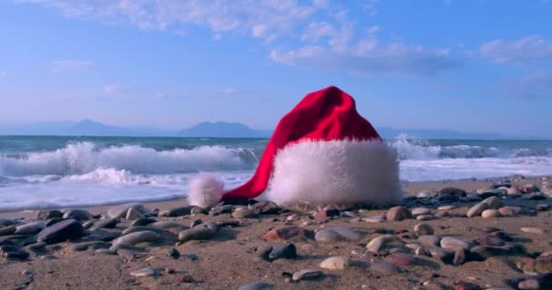 穏やかな波と熱帯の砂浜でクリスマスサンタクロースの帽子 冬休みだ島での新年のお祝い コンセプト — ストック動画