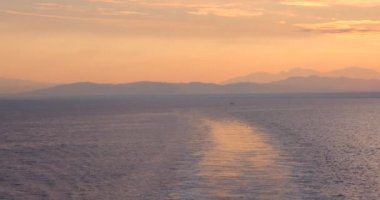 Gemi güvertesinden deniz dalgaları ve gökyüzünde sabah güneşinin doğuşunu seyret. Güneş 'in doğuşunun arka planına karşı küçük dalgalarla deniz yüzeyinin yavaş hareketi. Suyun üzerindeki güneş yolu. Altın ışık. Panorama