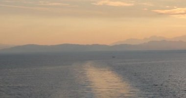 Gemi güvertesinden deniz dalgaları ve gökyüzünde sabah güneşinin doğuşunu seyret. Güneş 'in doğuşunun arka planına karşı küçük dalgalarla deniz yüzeyinin yavaş hareketi. Suyun üzerindeki güneş yolu. Altın ışık. Panorama