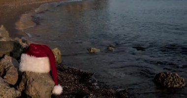 Tropikal kumlu sahilde sakin dalgalarla Noel Baba şapkası. Kış tatili Adada yeni yıl kutlaması. Kavram