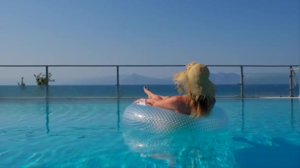Vrouw zwemt in een cirkel in het zwembad. Meisje drijft met een opblaasbare cirkel in het zwembad — Stockvideo