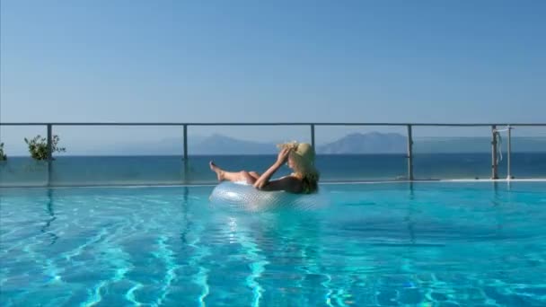 Frau schwimmt im Pool im Kreis. Mädchen schwimmt mit aufblasbarem Kreis im Schwimmbad — Stockvideo