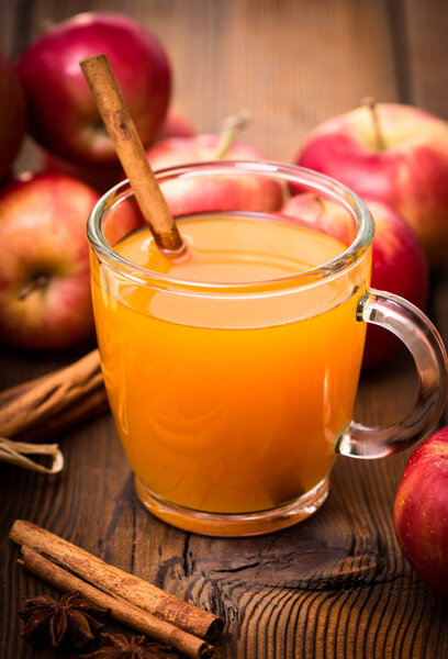 close up view of apple juice with cinnamon on wooden background