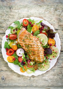 ahşap arka planda ev yapımı ızgara balık ve taze sebzeler