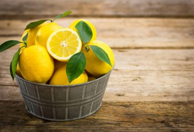 ahşap masa üzerinde metal kovada taze limon görünümü kadar kapatın