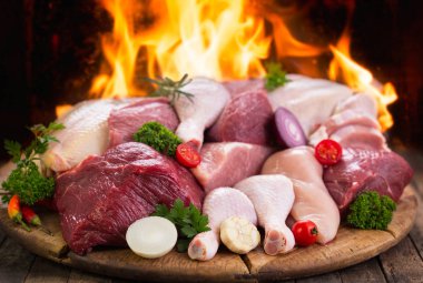 alev arka plan ile ahşap masa üzerinde sebze ile çeşitli çiğ et görünümü kadar kapatın