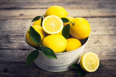 ahşap masa üzerinde metal kovada taze limon görünümü kadar kapatın