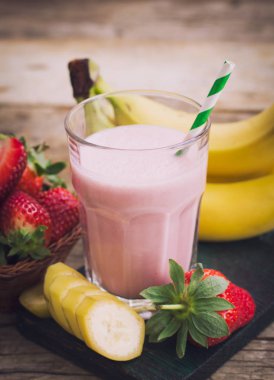 ahşap arka planda çilek ve muz ile lezzetli milkshake içecek görünümü yakın