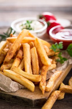 patates kızartması ve ahşap masanın üzerine düzenlenmiş soslar