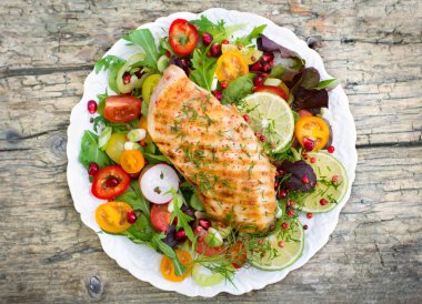 ahşap arka planda ev yapımı ızgara balık ve taze sebzeler