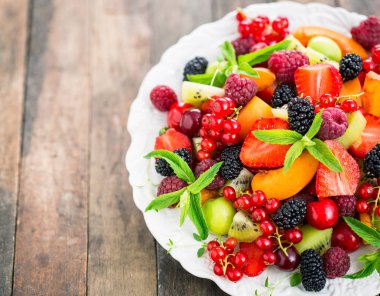 ahşap arka planda kase taze meyve ve çilek görünümü yakın
